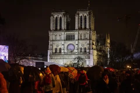 A crowd gathers outside the Notre-Dame Cathedral in Paris to watch its reopening ceremony on Saturday on a giant screen on the banks of the River Seine.